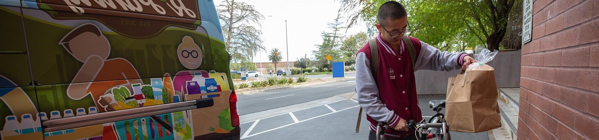 UCR student receives a bag of groceries from R'Pantry